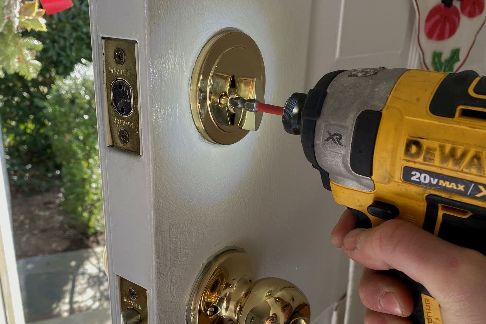 Drill driver turning the screws on a brass deadbolt