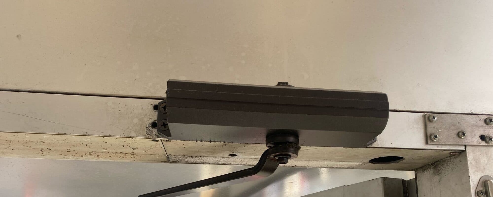 Door closer fitted on a metal-framed glass door
