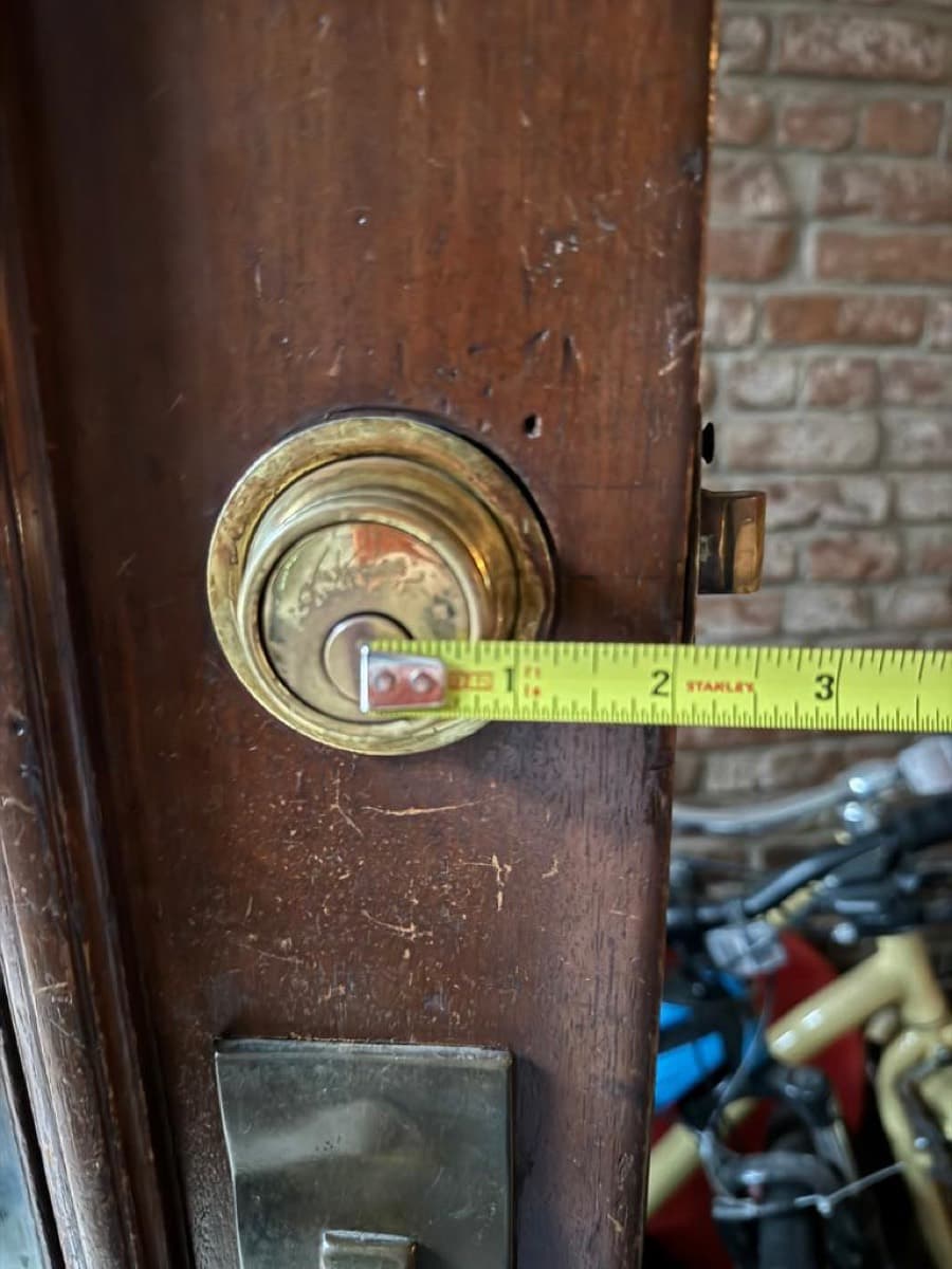 Old mortise cylinder being measured before replacement